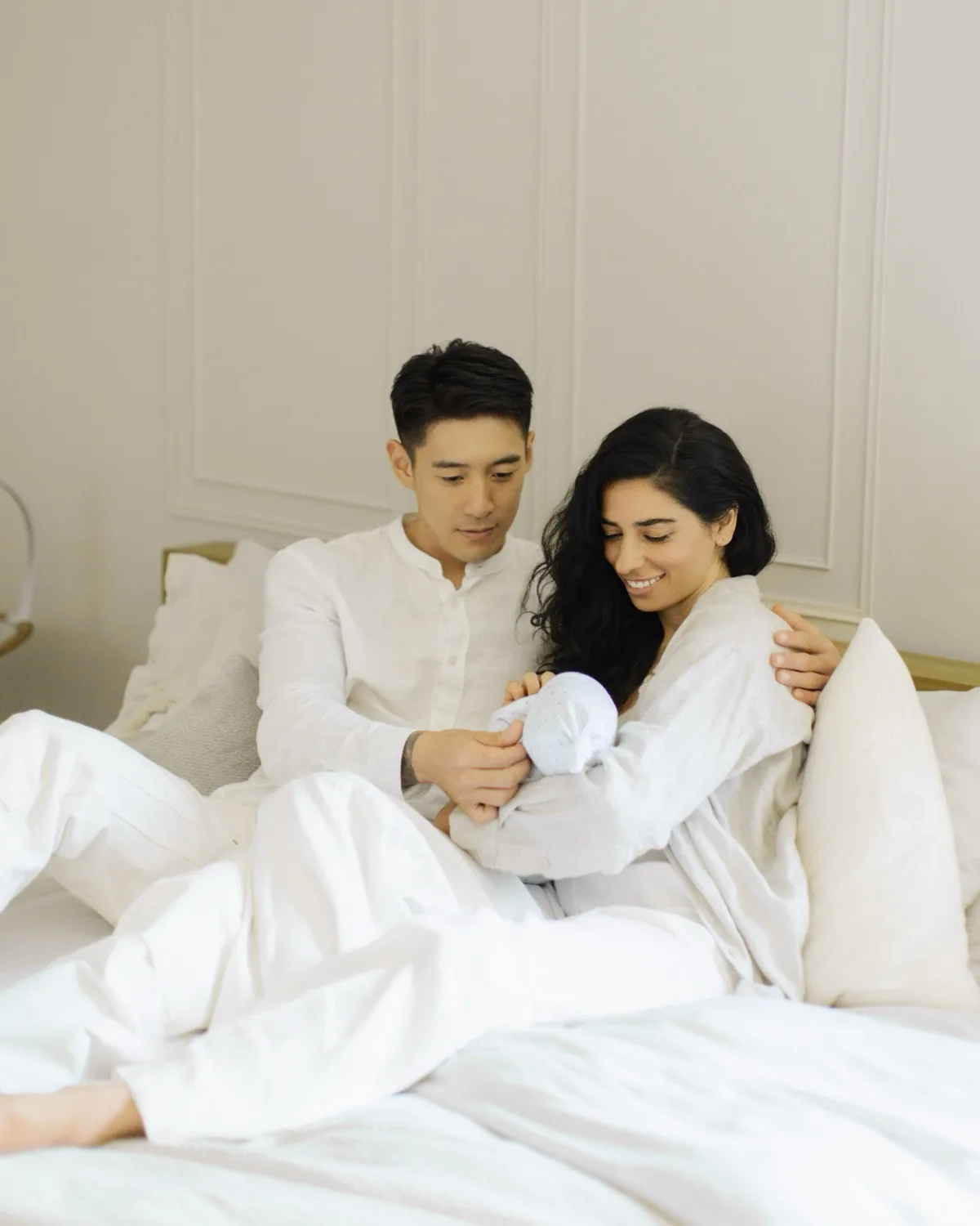 Parents at home in bed, holding their newborn